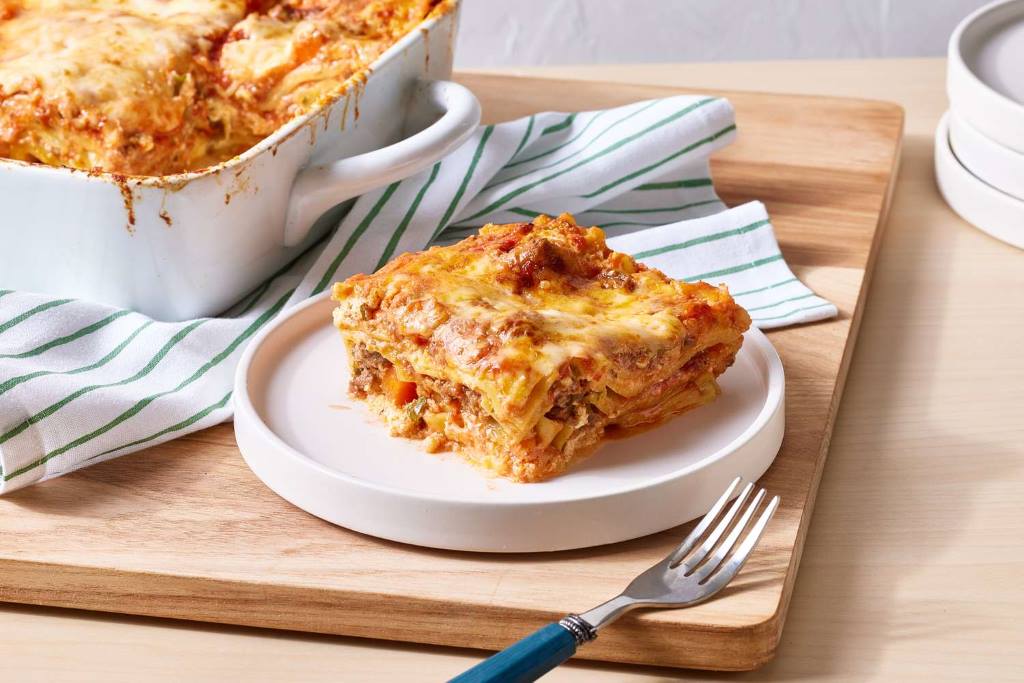 Layered lasagna in a baking dish with meat sauce and cheese mixture