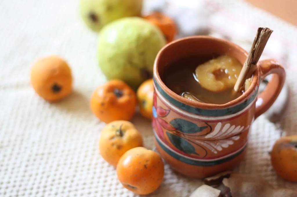 Step-by-step ingredients for authentic ponche Navideño recipe laid out on wooden table