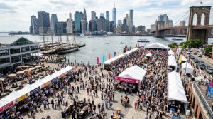 Aerial view of the NYC Wine and Food Festival at the Seaport waterfront with guests sampling food and wine at outdoor tasting stations